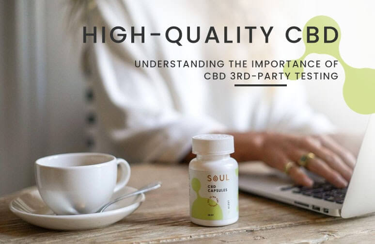 Banner showing Soul CBD capsules bottle on a wooden table with a coffee cup and a blurred person using a laptop