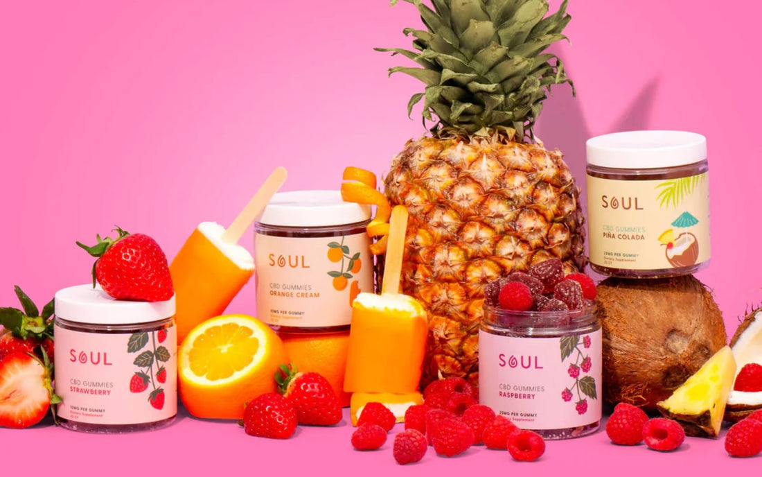 Front view of Soul CBD gummies jars showing flavor labels with fresh fruit and popsicles on pink background