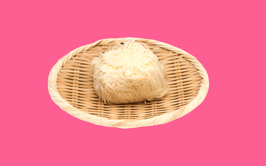 Lion’s mane mushroom cluster resting on a woven bamboo tray against a pink background