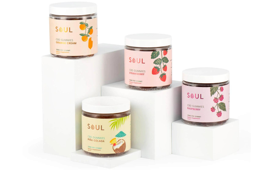 Front view of four Soul CBD gummies jars showing Orange Cream, Strawberry, Piña Colada, and Raspberry labels on white display blocks