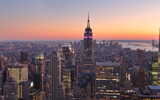 Empire State Building and Midtown Manhattan skyline at sunset with orange and purple sky