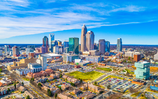 Aerial view of Charlotte skyline with downtown skyscrapers and a bright blue sky