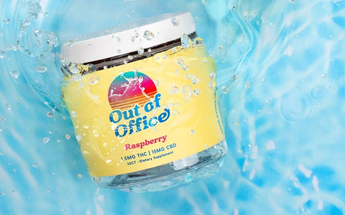 Tilted close up of Out of Office Raspberry jar with yellow label showing 1.5MG THC and 15MG CBD against splashing blue water