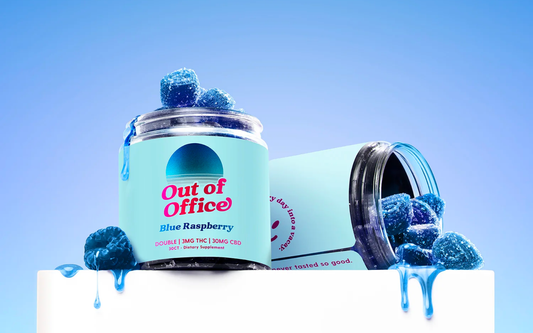 Three-quarter view of Out of Office Blue Raspberry THC gummy jars with sugar-coated blue gummies spilling and blue syrup on a pale blue background