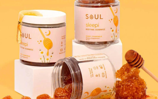 Front and angled view of Soul Sleepi bedtime gummy jars showing honey chamomile label and spilled honey-dipped gummies on orange background