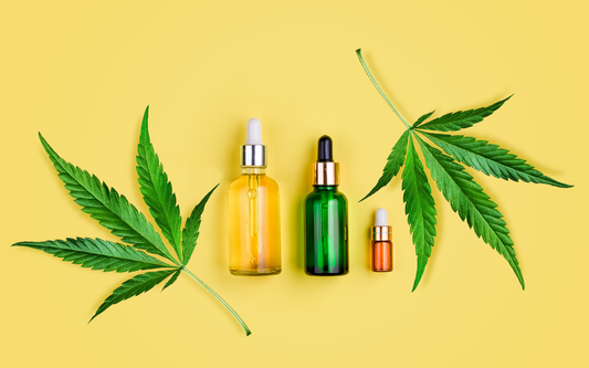 Three dropper tincture bottles displayed between two cannabis leaves on a yellow background