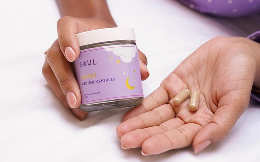 Close-up of Soul Sleepi bedtime capsules jar showcasing two capsules in a hand on a white sheet