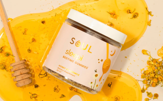 Angled top-down view of Soul sleepi bedtime gummies jar showing Honey Chamomile label on a honey spill with chamomile flowers and honey dipper