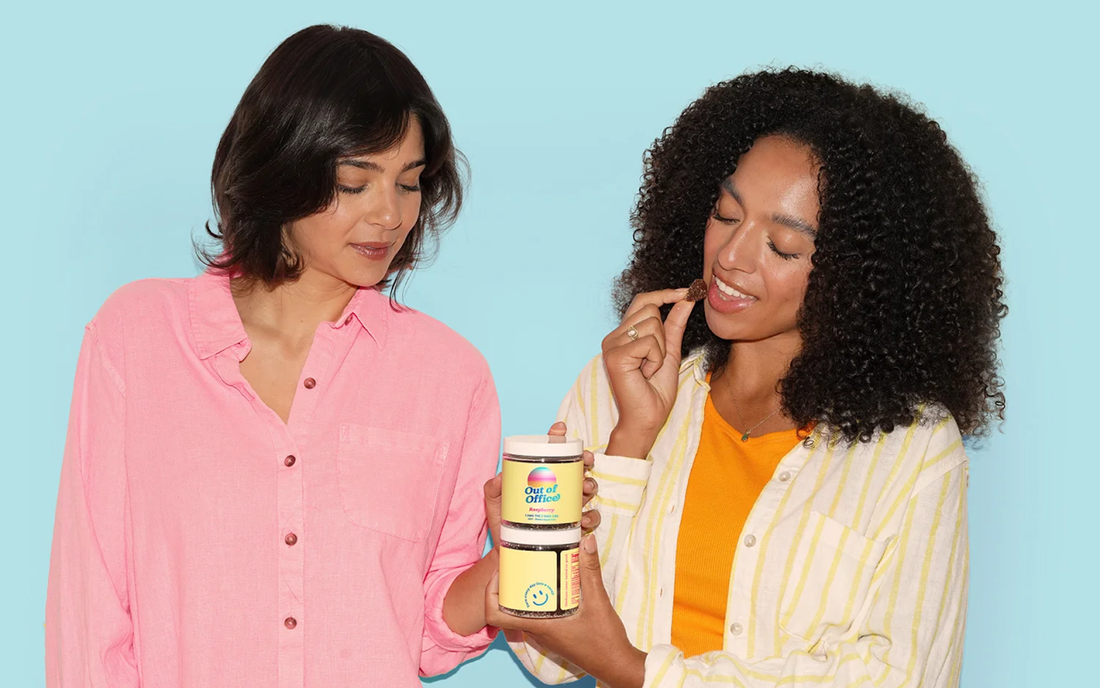 Two women sharing and sampling Out of Office raspberry gummies against a pale blue background