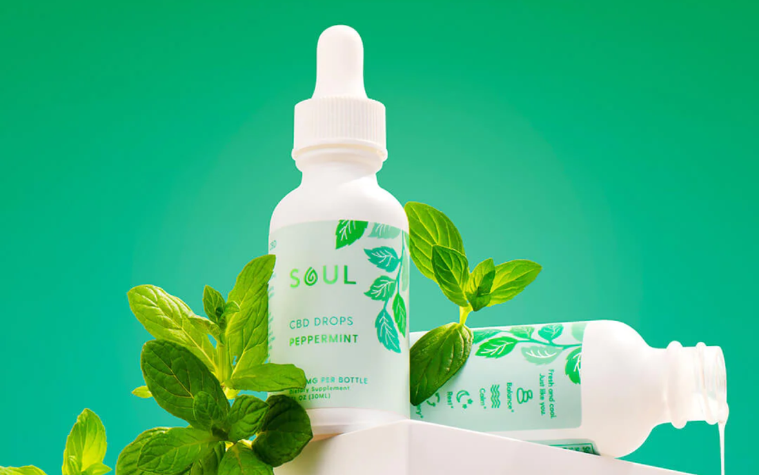 Front view of Soul peppermint CBD drops bottle with fresh mint leaves on green gradient background