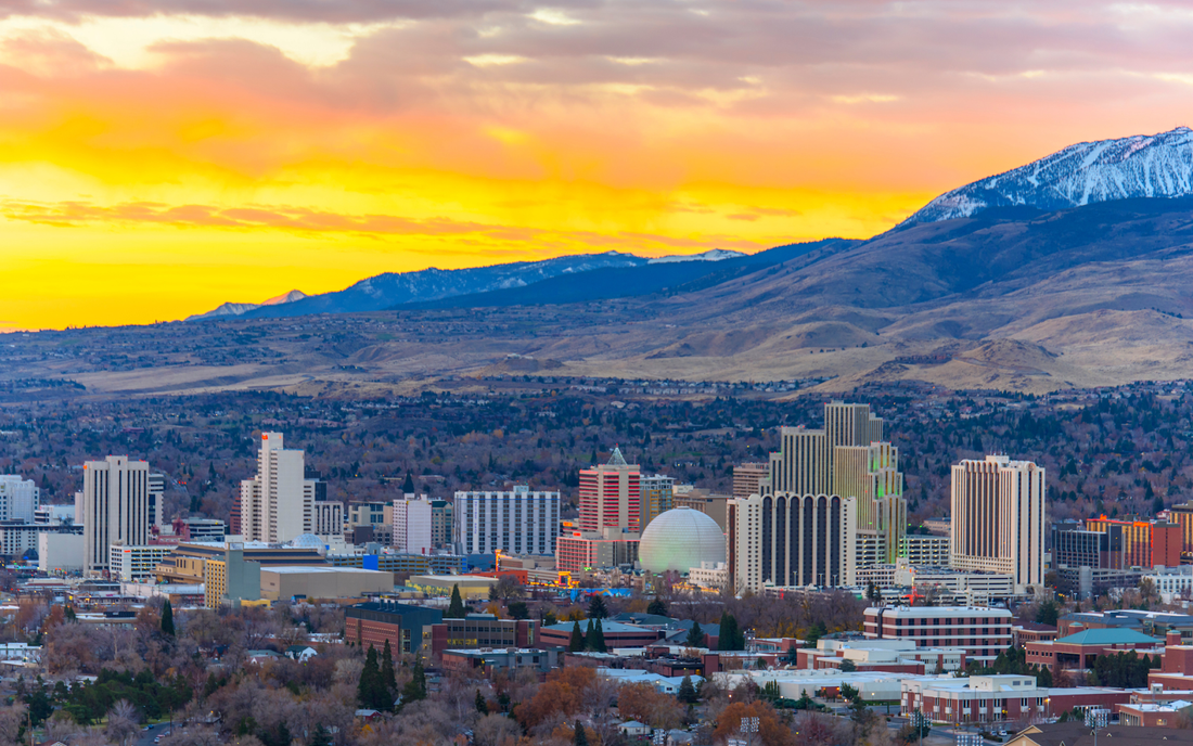 Nevada city skyline at sunset showing downtown high-rise buildings and mountains in the background