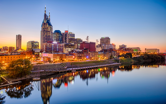 Nashville skyline at sunset with downtown buildings reflecting on the Cumberland River