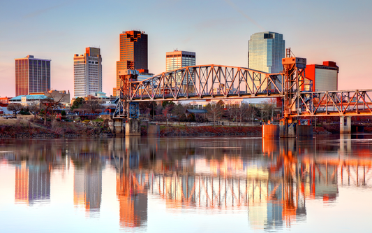City skyline with a steel lift bridge at sunset reflected in a calm river