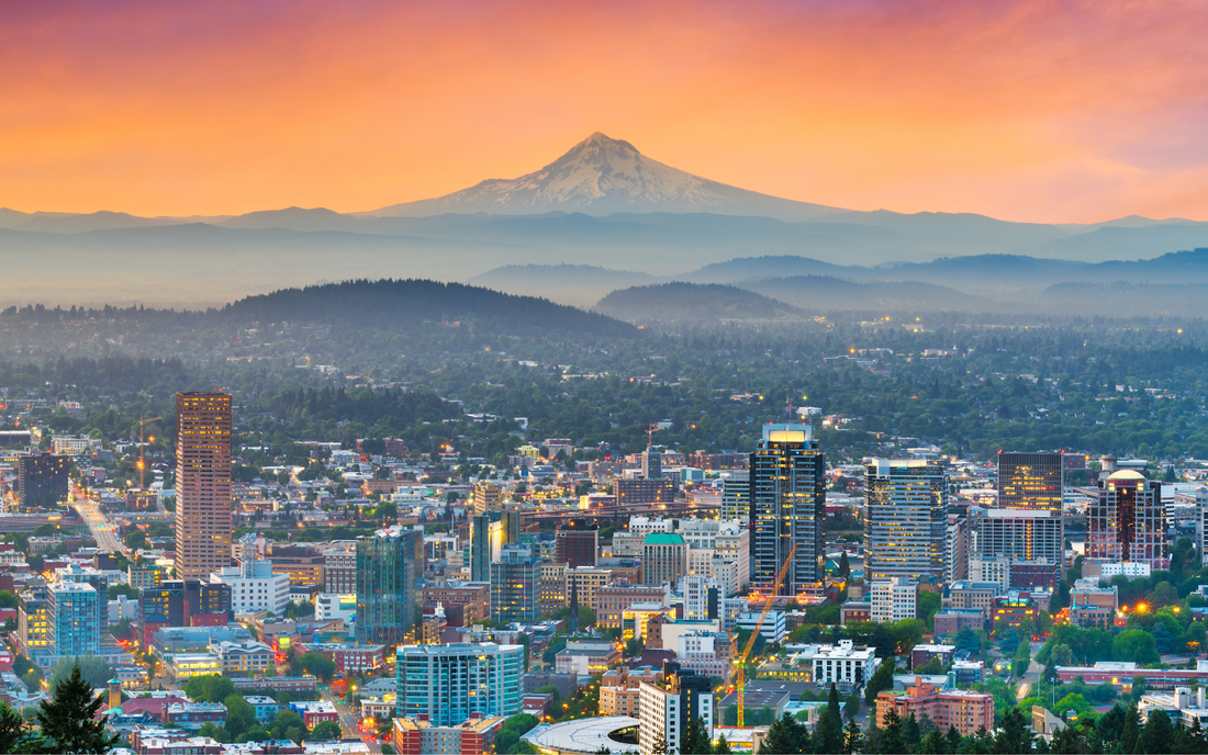 Portland skyline at sunset with Mount Hood rising over layered hills