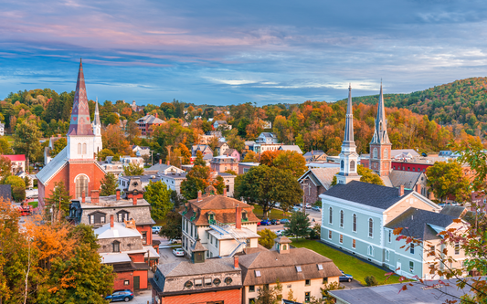 Small-town Vermont skyline at sunset showing church steeples and colorful autumn foliage