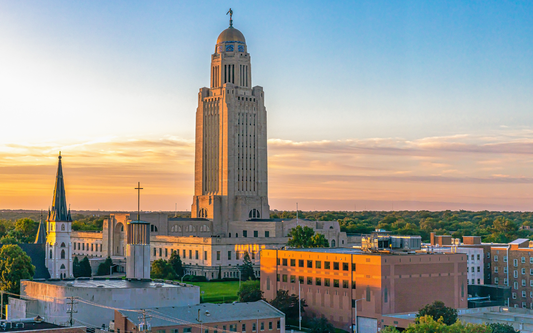 Nebraska State Capitol building at sunset with warm golden sky
