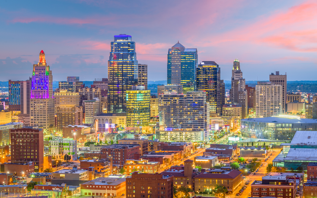Kansas City skyline at sunset with illuminated downtown high-rises and pink clouds