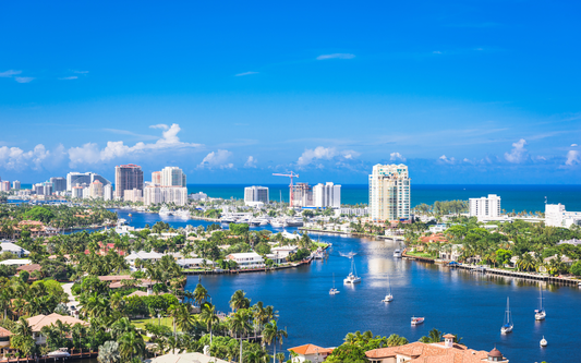 Aerial view of a Florida coastal city with canals, sailboats, waterfront homes and high rise condos on a sunny day