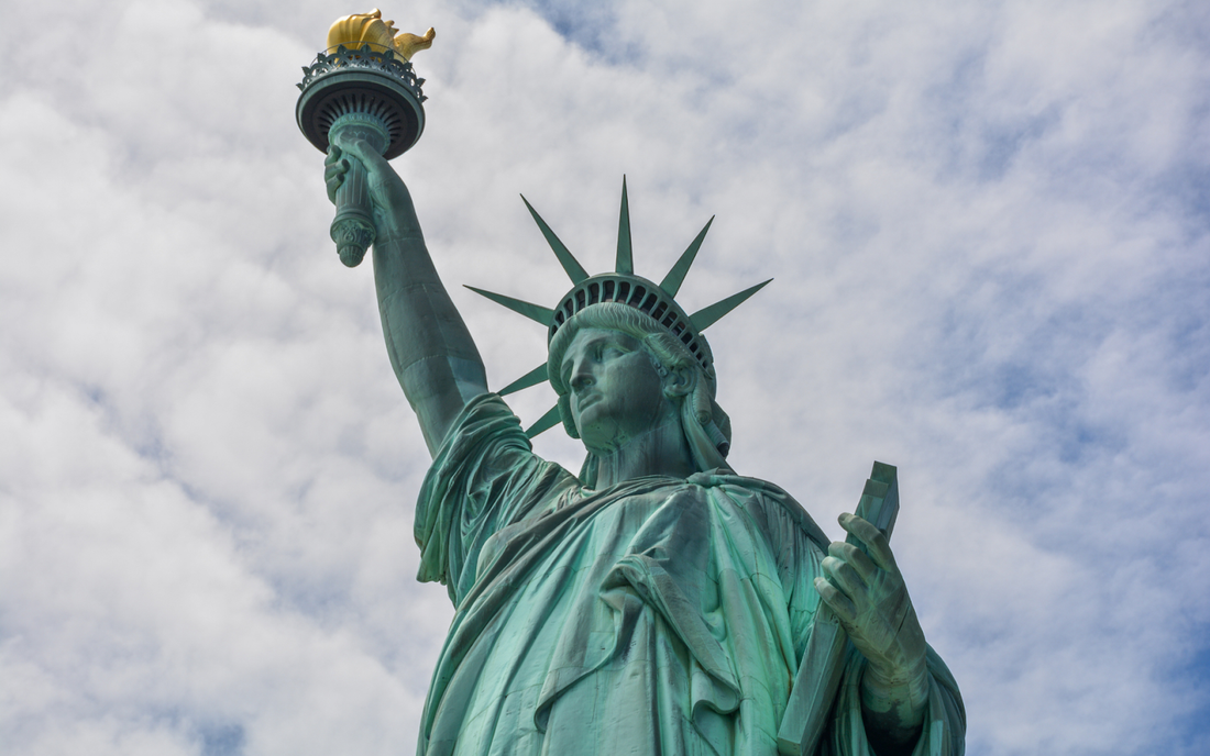 Statue of Liberty holding her torch and tablet against a cloudy sky
