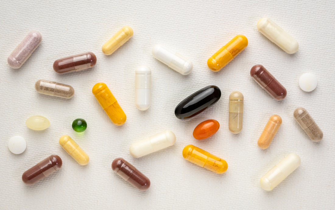 Assorted supplement capsules and tablets scattered on a white textured fabric background