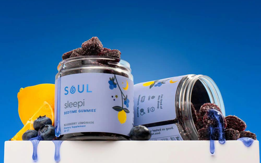 Front view of Soul Sleepi Bedtime Gummies jar with blueberry-lemonade sugar-coated gummies spilling on a blue background