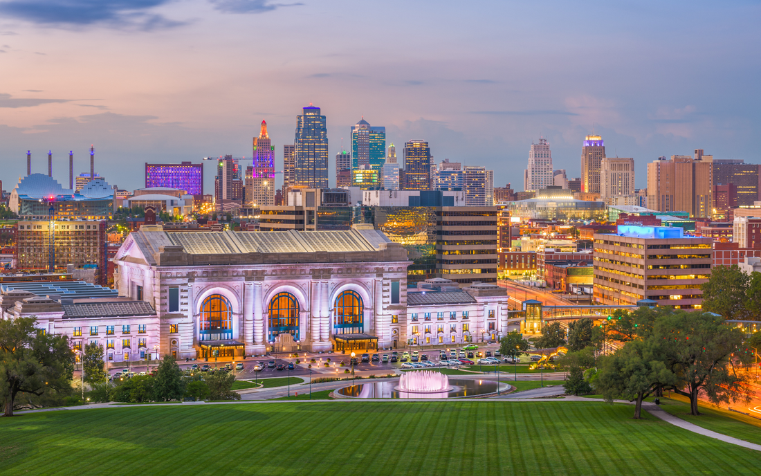 Kansas City skyline at dusk with illuminated Union Station and a lit fountain in the foreground