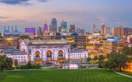 Kansas City skyline at dusk with illuminated Union Station and a lit fountain in the foreground