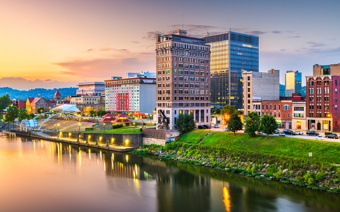 Downtown West Virginia riverfront skyline at sunset with lit promenade and riverside park