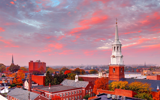 White church steeple overlooking a small Pennsylvania town with autumn trees and a soft pink sky