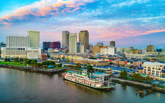 Riverboat docked on the Mississippi River with the New Orleans skyline and pastel sunset sky in the background