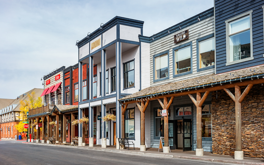 Small Wyoming main street with wooden storefronts, a gallery sign, hanging flower baskets, and a stop sign