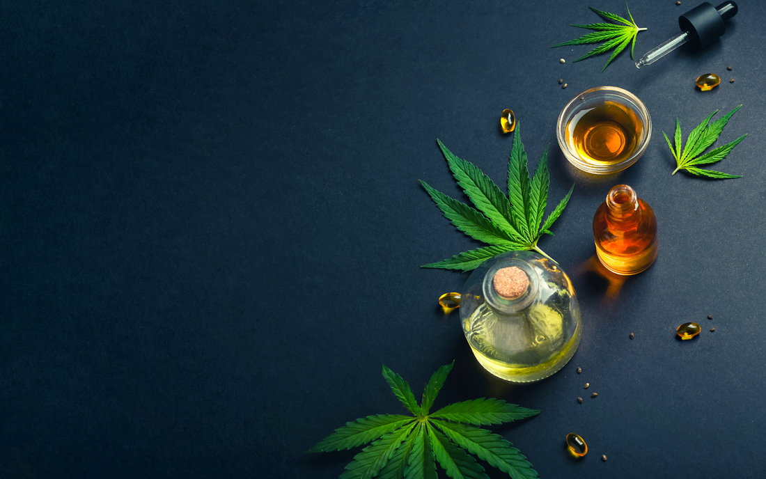 Hojas de cannabis y frascos de aceite de marihuana sobre fondo oscuro