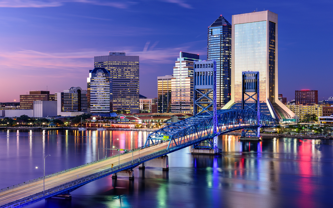 Vista nocturna del skyline de una ciudad de Florida con un puente metálico iluminado sobre el río al atardecer