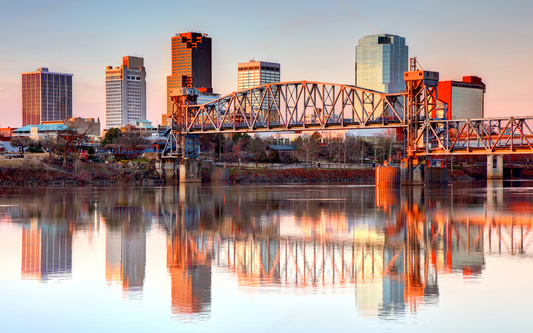 Little Rock skyline at sunset with downtown skyscrapers and a steel lift bridge reflected in the Arkansas River