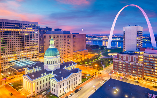 Gateway Arch and St. Louis skyline at sunset with the Old Courthouse dome and lit city streets