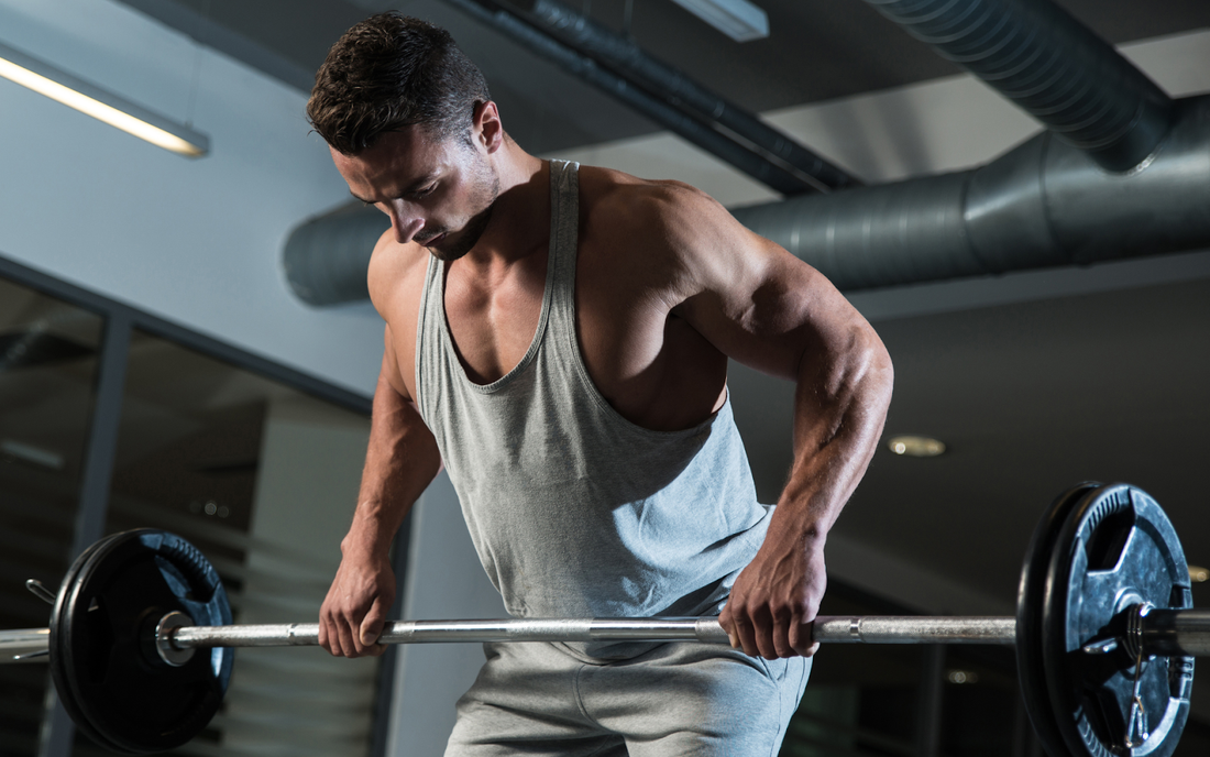 Man performing a bent-over barbell row in a gym, emphasizing back and arm muscles