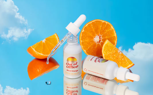 Front view of Out of Office Blood Orange tincture bottle with dropper, reflected on bright blue background with sliced oranges