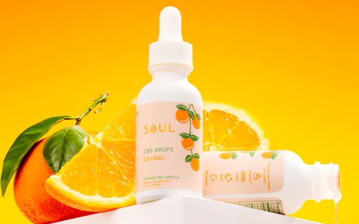Front view of Soul CBD Drops bottle showcasing orange-flavored tincture with sliced oranges and bright orange background