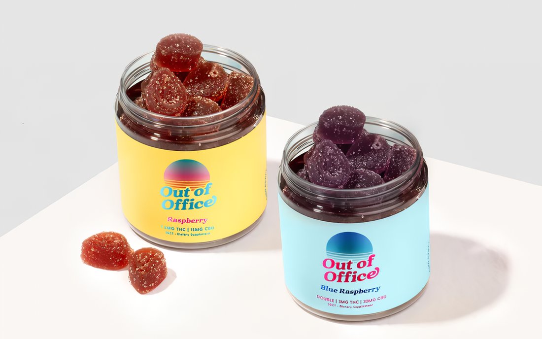 Angled top view of two open Out of Office jars showing sugar-coated raspberry and blue raspberry gummies on a white surface