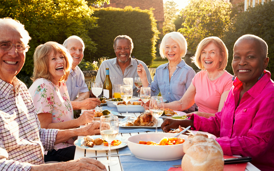 Group of older adults enjoying a sunlit outdoor meal together at a garden table