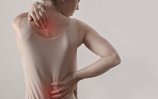 Woman holding her neck and lower back, indicating upper and lower back pain with red pain highlights on a neutral background
