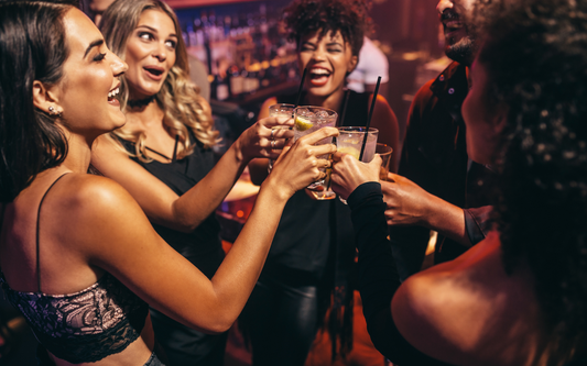 Group of friends toasting with mixed drinks at a dimly lit bar