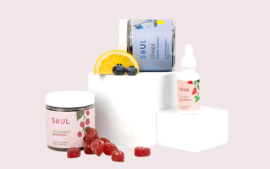 Front view of Soul CBD products including raspberry gummies jar and watermelon-mint oil dropper on pale pink background