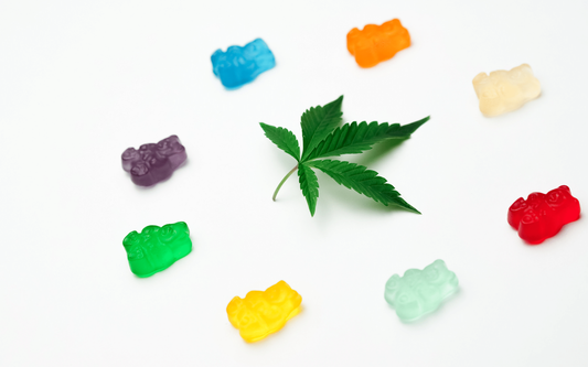 Green cannabis leaf surrounded by colorful gummy bear edibles on a white background