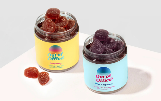 Angled top view of two open Out of Office gummy jars showing sugar-coated raspberry and blue raspberry gummies on a white background