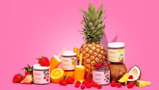 Front view of Soul CBD gummies jars showing flavor labels (strawberry, orange cream, raspberry, pina colada) with fruit on pink background