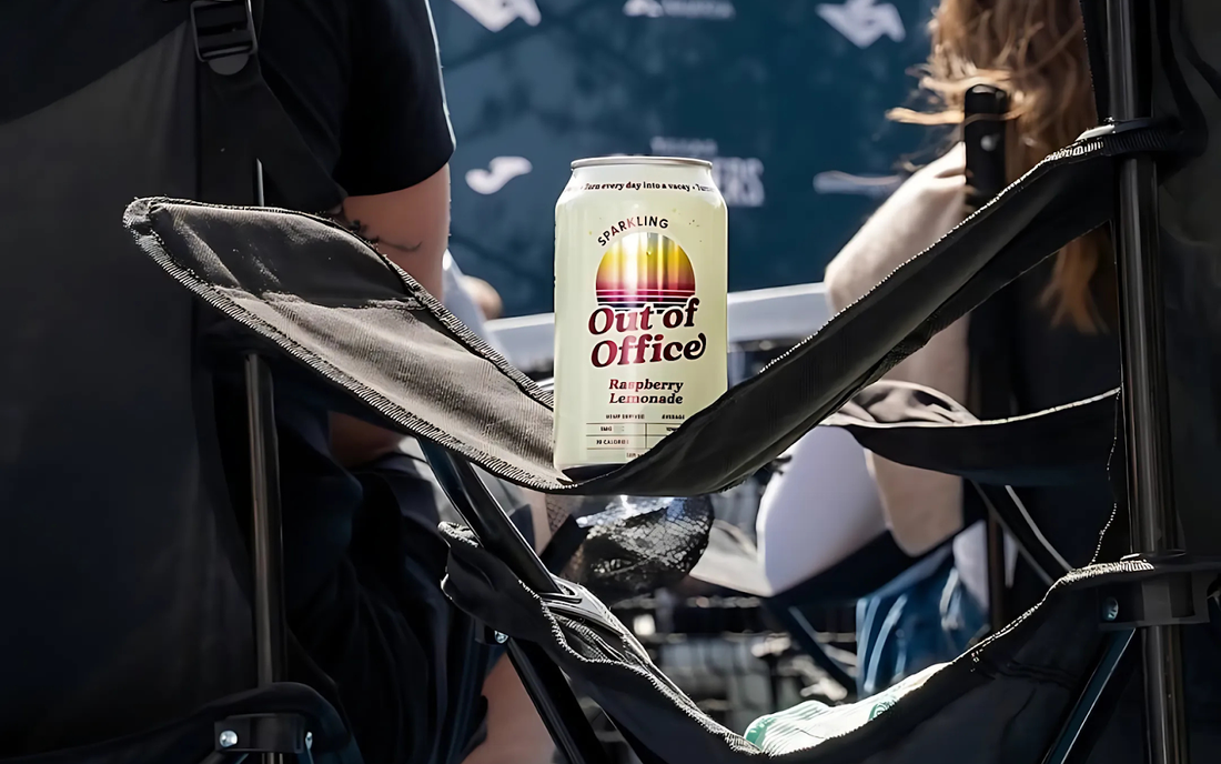 Can of Out of Office Raspberry Lemonade resting in a folding chair cup holder at an outdoor event
