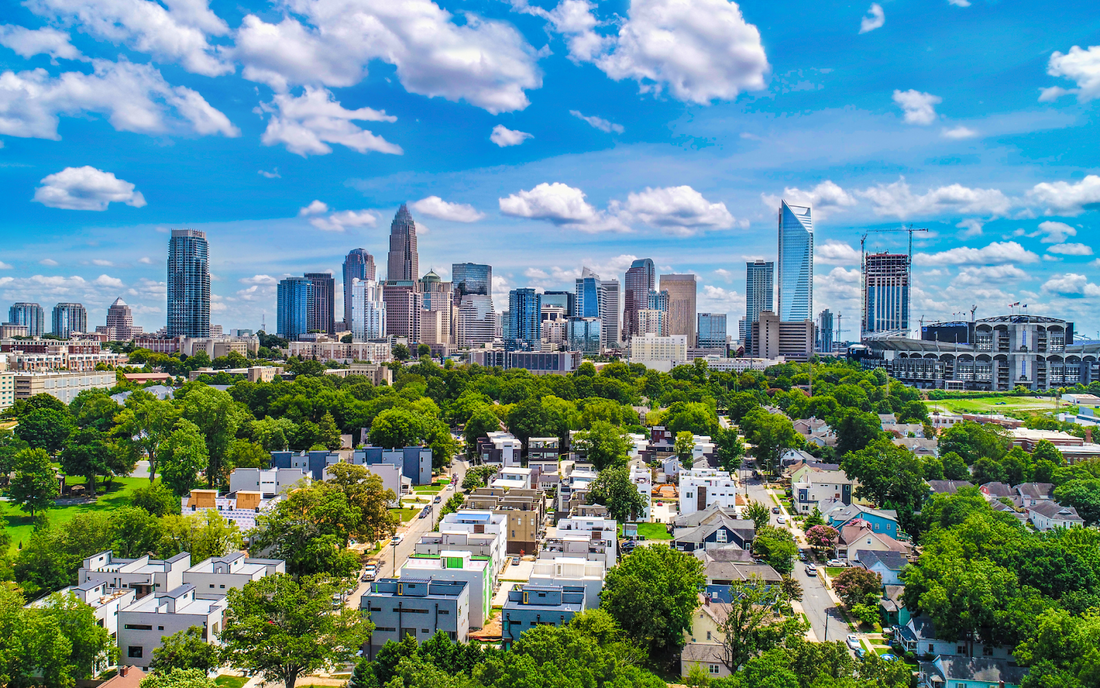 Aerial view of Charlotte skyline above a residential neighborhood on a sunny day