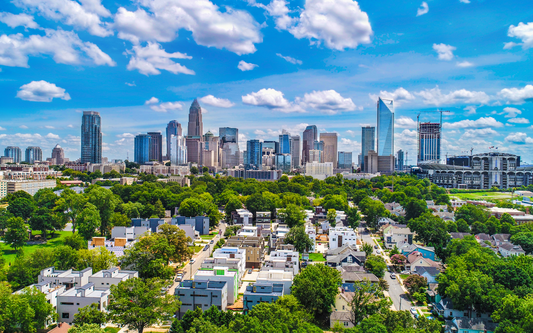 Aerial view of Charlotte skyline above a residential neighborhood on a sunny day