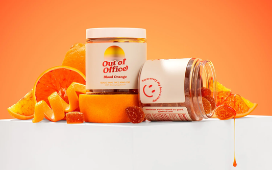 Front and side view of Out of Office Blood Orange gummy jars with sugar-coated gummies and sliced blood oranges, label reads 10MG THC 45MG CBD